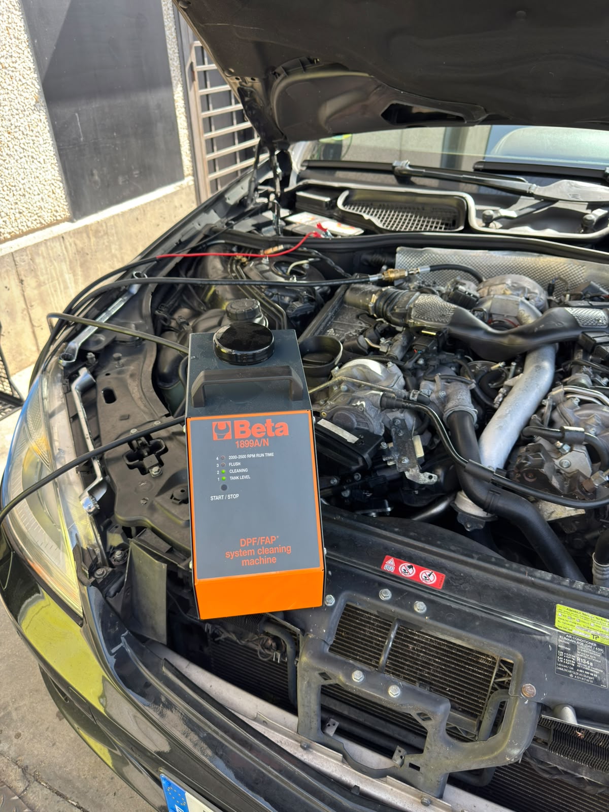 Máquina profesional de limpieza DPF/FAP conectada al motor de un vehículo en nuestro taller